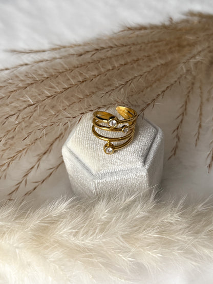 Mehrreihiger Goldring (Edelstahl vergoldet) mit funkelnden Zirkonia-Steinen in Solitär-Optik. Modernes Design mit zwei Akzentsteinen auf schlichtem Band ~ Javi Jewelery